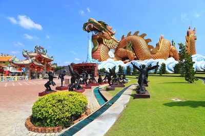 Statue of people in park against sky