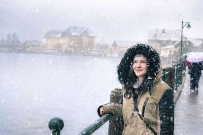 Young woman standing on frozen lake in city during winter