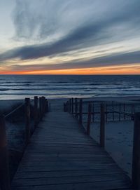 Wooden pier on sea against sky during sunset