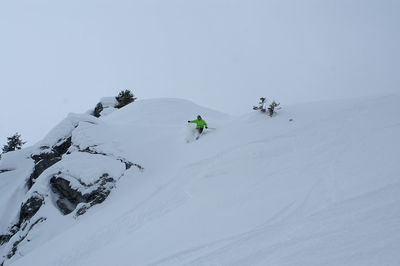 Person skiing on snowcapped mountain against sky