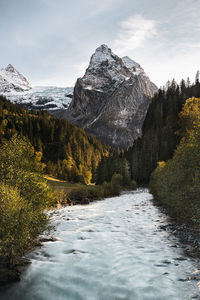 Scenic view of river against snowcapped mountains and sky