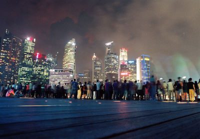 People on road against illuminated buildings