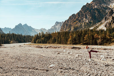 Happy woman dancing on land against mountains