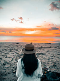 Rear view of woman in sea against sky during sunset