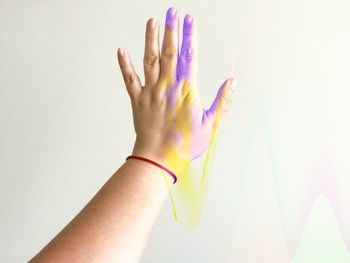 Cropped hand with colorful paints against white background