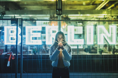 Portrait of woman holding illuminated string light at night