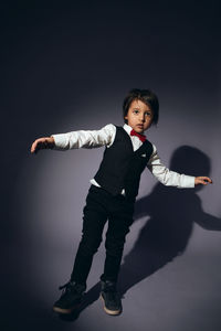 Stylish boy child of four years in the studio on the background in a vest and a red bow tie