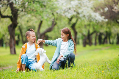 Happy friends sitting on grass against trees