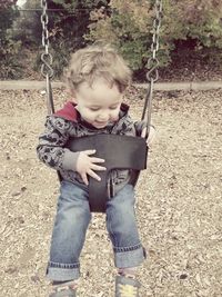 Little boy sitting on swing at playground