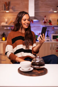 Young woman using phone while sitting on table