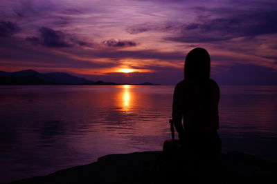 Silhouette man looking at sea against sunset sky