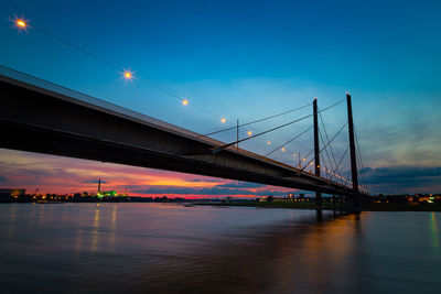 Bridge over river against sky at sunset