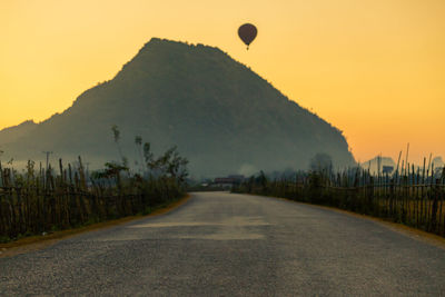 Road by hot air balloon against sky during sunset