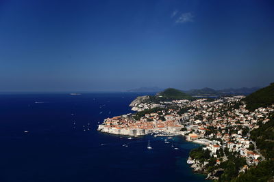 High angle view of townscape by sea against blue sky