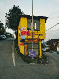 Road sign on street in city against sky