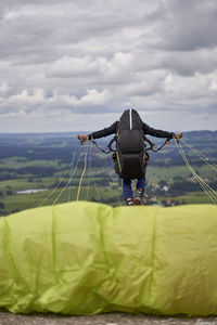 Rear view of man standing on rope against sky