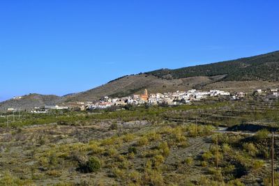 Scenic view of civilization within nature landscape against clear sky