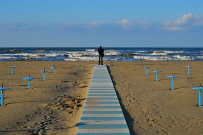 Man standing at beach against sky