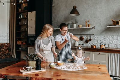 Funny happy dad and daughter baby cook together fool around and play with flour in  kitchen at home