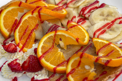 Pancakes with cranberry jam, strawberries, bananas, cream, and strawberry topping. closeup.