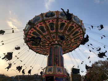 Low angle view of chain swing ride against sky