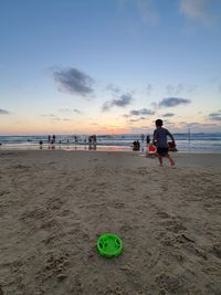 People on beach against sky during sunset