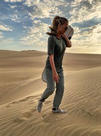 Full length of young woman standing on sand dune