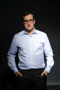 Portrait of young man standing against black background