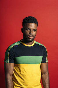 Portrait of young man standing against red background