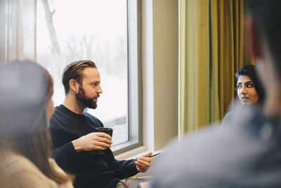 Confident businessman discussing with colleagues in board room meeting