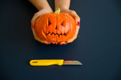 Close-up of hand holding pumpkin against black background