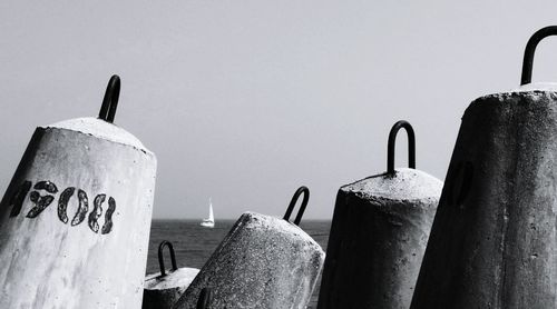 Tetrapods by sea against sky