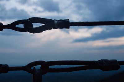 Close-up of padlocks on metal against sky