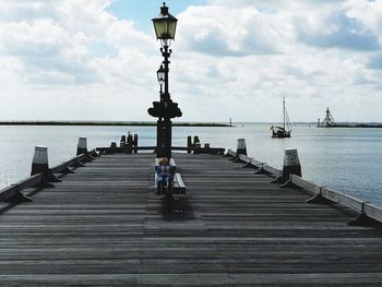 Rear view of man on pier at sea against sky