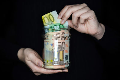 Close-up of hand holding candle against black background