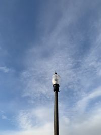 Low angle view of bird on pole against sky