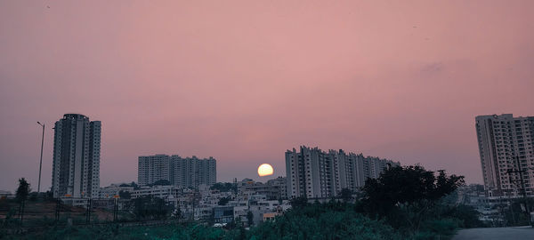 Buildings in city against sky at sunset