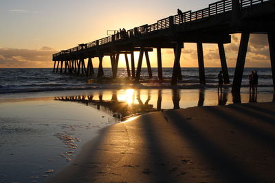 Silhouette wooden pier on sea against sky at sunset