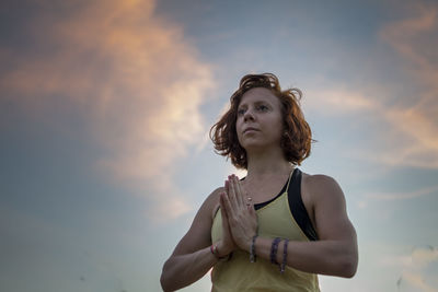 Woman exercising against sky