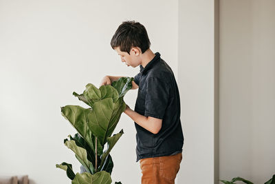 Side view of young man holding plant