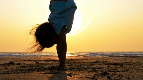 Woman on beach against sky during sunset