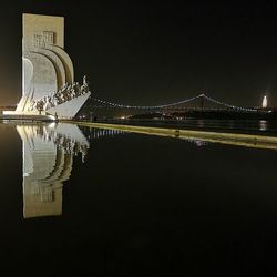 Illuminated bridge over river against sky at night