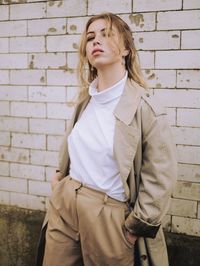 Beautiful young woman standing against brick wall