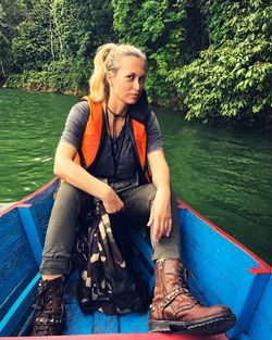 Portrait of confident hiker sitting in rowboat at lake