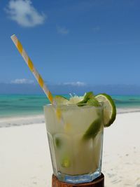 Close-up of drink on glass at beach against sky