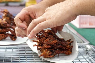 Close-up of hand holding meat on barbecue grill