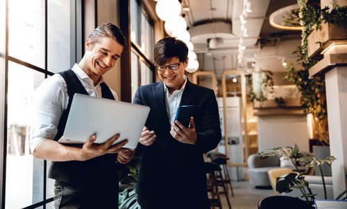 Smiling businessmen looking at laptop in office