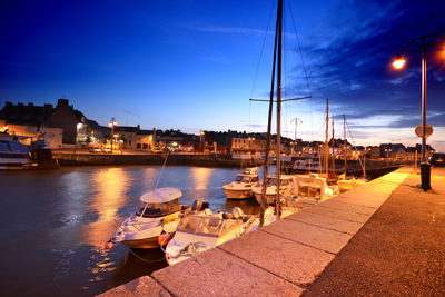 Boats moored at harbor in city at dusk