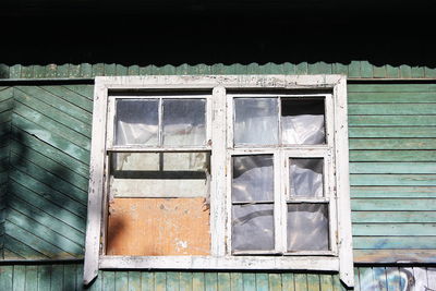 Low angle view of broken window of abandoned building