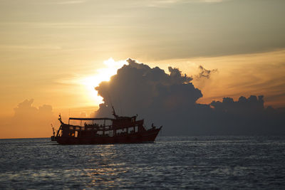 Tourist boat cruising against beautiful sunset sky